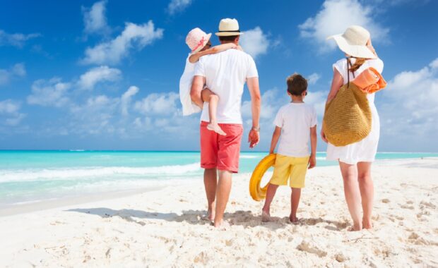 Back view of a happy family on tropical beach