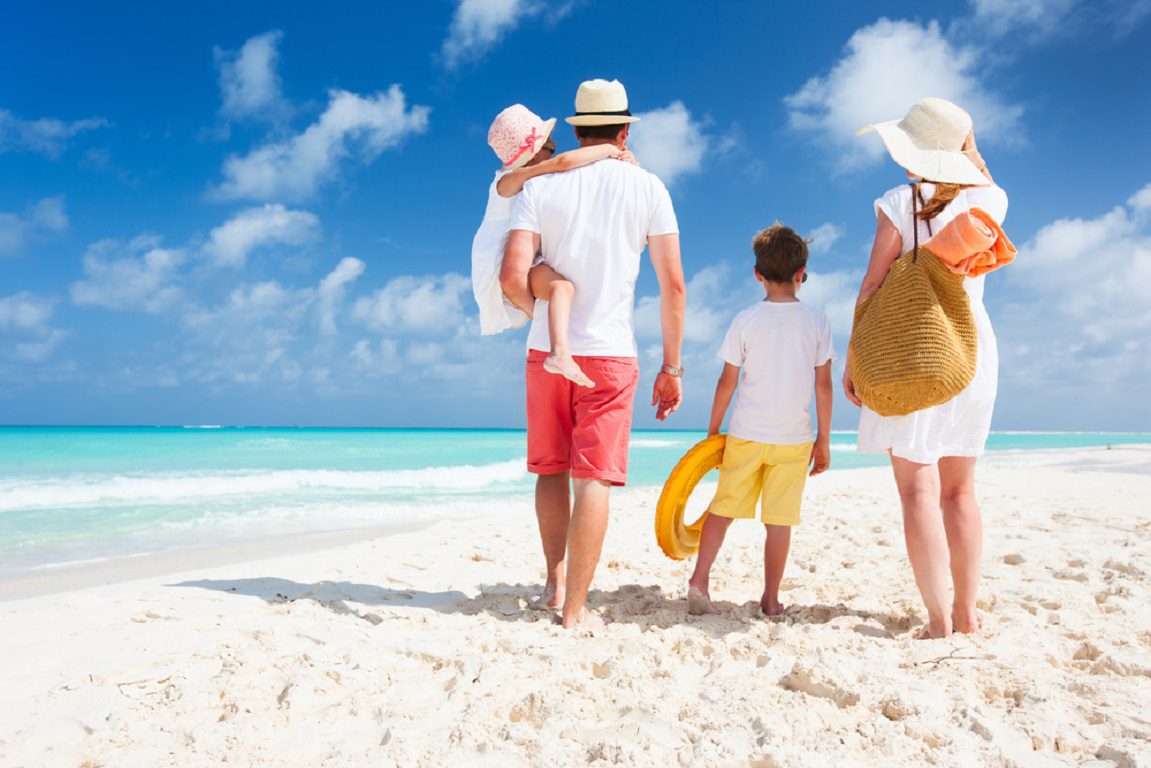 Back view of a happy family on tropical beach